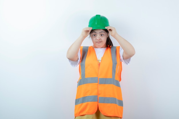 Jeune femme travailleur de la construction portant son casque vert sur mur blanc