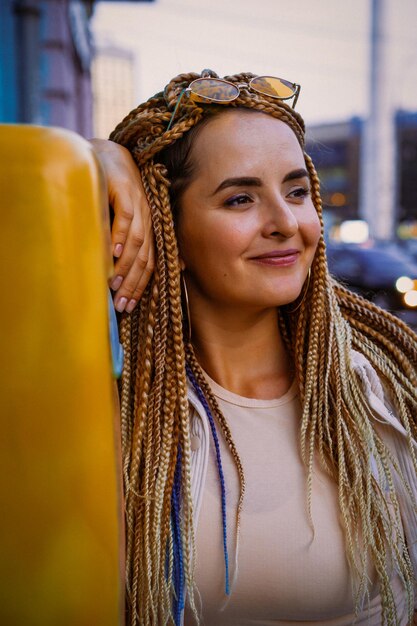 jeune femme avec des tresses afro zizi et un maquillage lumineux dans une grande ville, portrait. coiffures de tresses zizi.