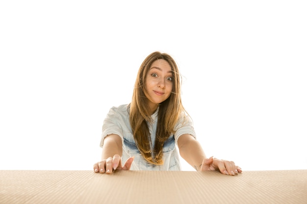 Jeune femme triste ouvrant le plus gros colis postal isolé sur mur blanc