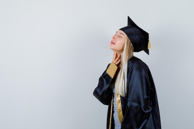 Jeune femme en uniforme diplômé examinant la peau de son cou et semblant délicate.