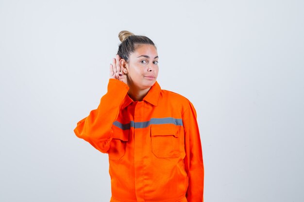 Jeune femme en uniforme de travailleur à l'écoute et à la vue attentive, de face.