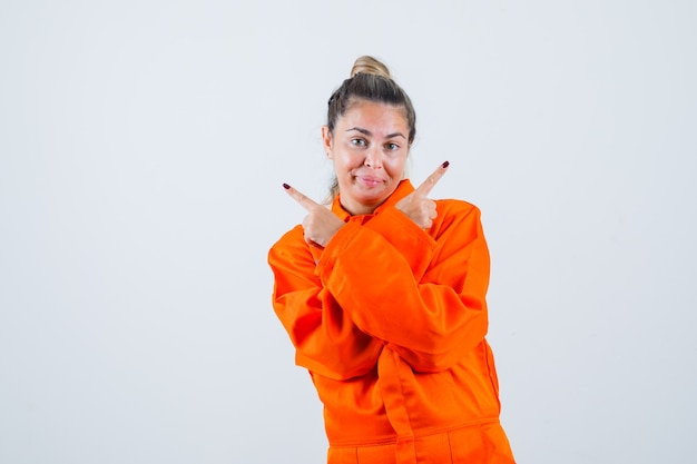 Photo gratuite jeune femme en uniforme de travailleur pointant vers la gauche et la droite et à la confusion, vue de face.