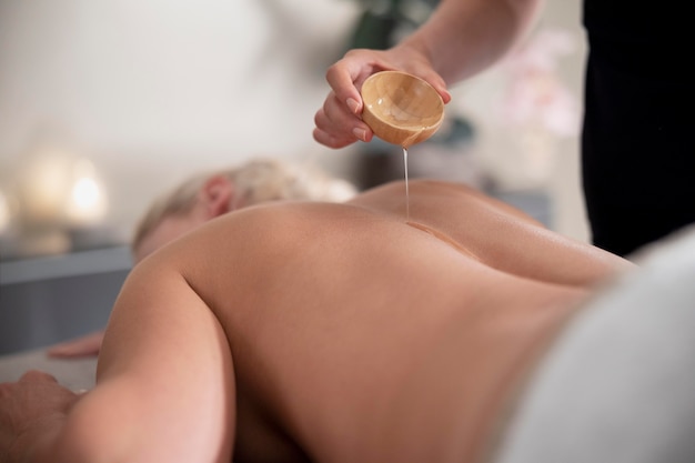 Jeune femme utilisant de l'huile de massage sur son client