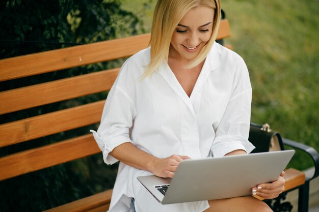 Jeune femme utilisant un ordinateur portable et un téléphone intelligent. Belle étudiante travaillant sur ordinateur portable en plein air