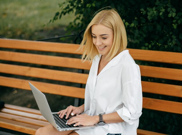 Jeune femme utilisant un ordinateur portable et un téléphone intelligent. Belle étudiante travaillant sur ordinateur portable en plein air