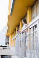Photo gratuite jeune femme, utilisation, smartphone, debout, balcon