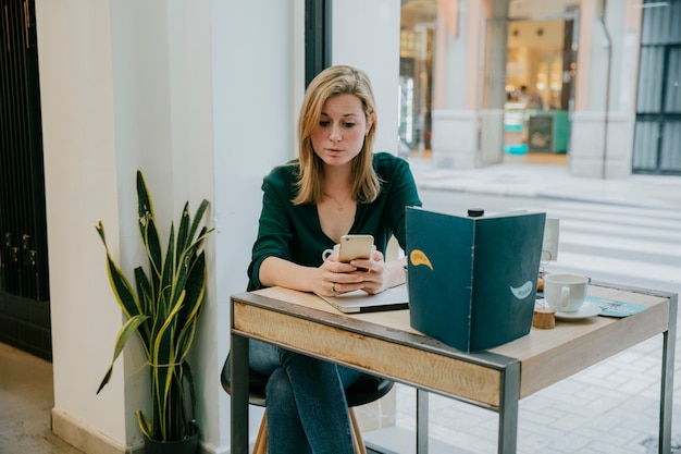 Jeune femme, utilisation, smartphone, près, café, fenêtre