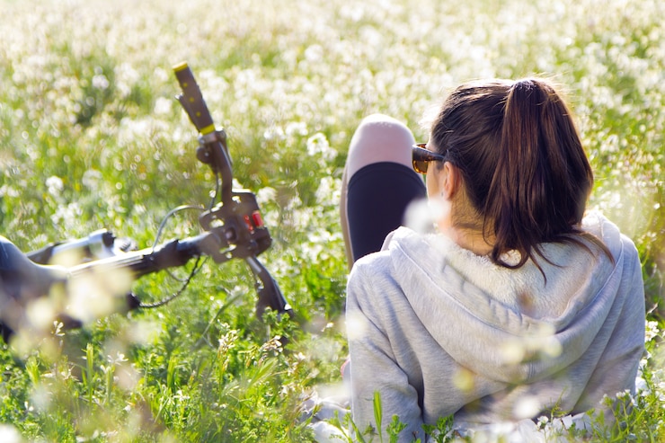 Photo gratuit jeune femme avec un vélo de montagne tendu sur le terrain