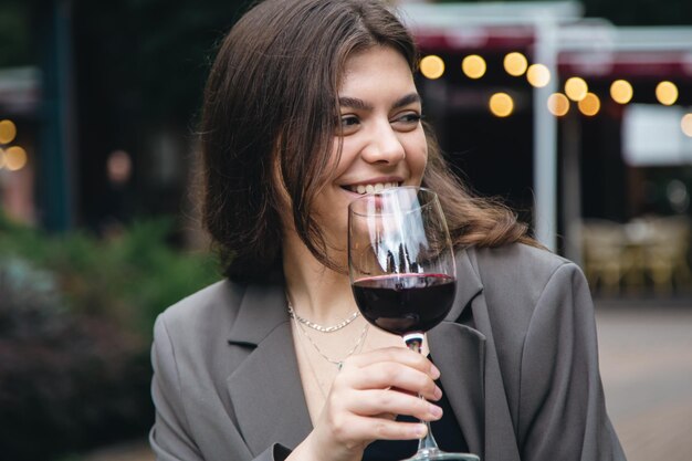 Une jeune femme avec un verre de vin à l'extérieur près d'un restaurant