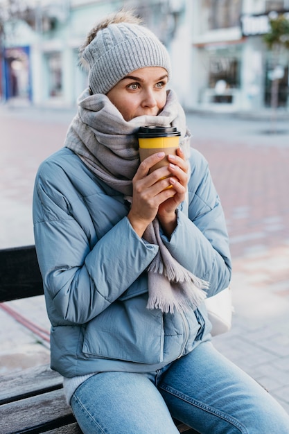 Jeune femme en vêtements d'hiver tenant une tasse de café