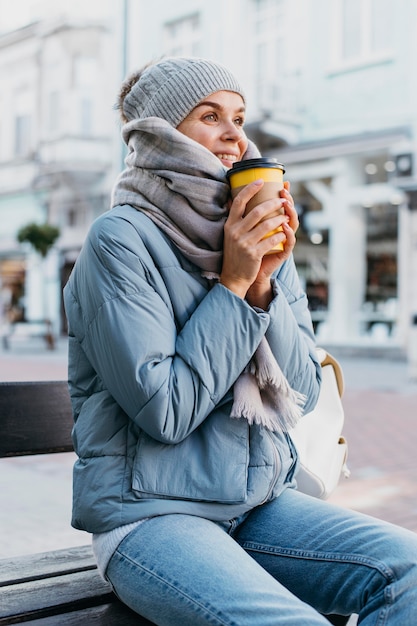 Photo gratuite jeune femme en vêtements d'hiver tenant une tasse de café