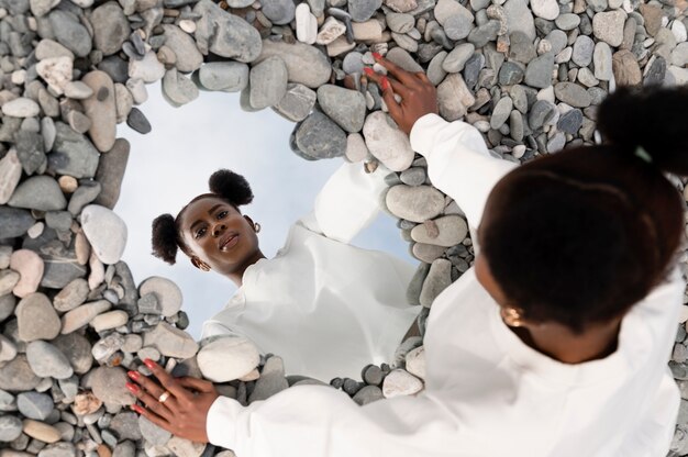 Jeune femme vêtue de blanc posant avec miroir dans les rochers