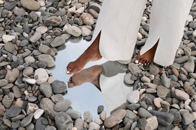 Jeune femme vêtue de blanc posant avec miroir dans les rochers