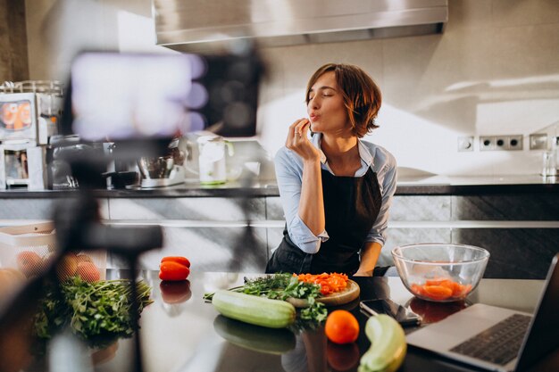 Jeune femme vidéoblogger en train de cuisiner à la cuisine et de filmer