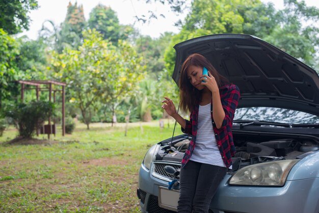 Une jeune femme avec une voiture se décompose et elle appelle les services d&#39;urgence.