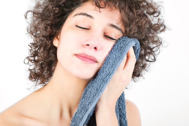 Jeune femme avec des yeux fermés, essuyant le corps avec une serviette isolée sur fond blanc