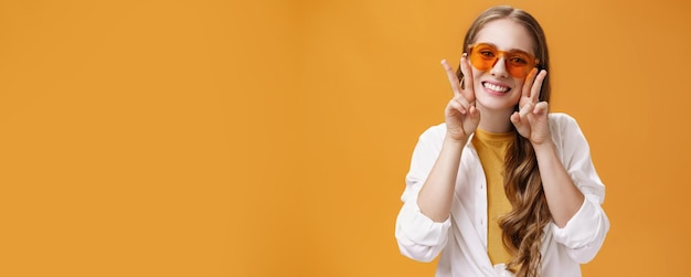 Jeune fêtarde élégante et charismatique avec des lunettes de soleil à la mode et un chemisier blanc sur tsh