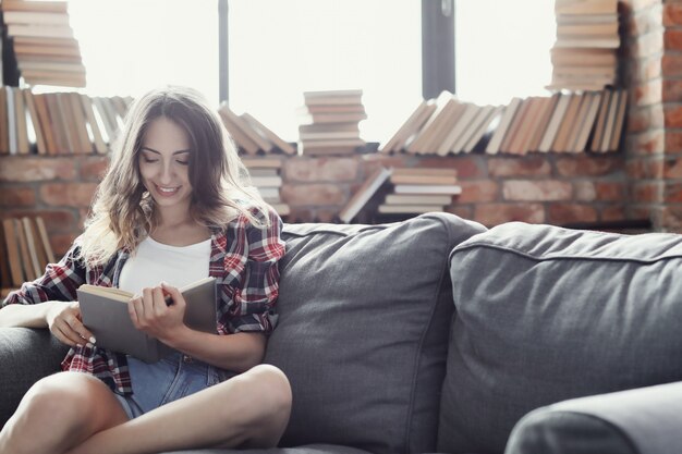 Jeune fille adolescente lisant un livre à la maison