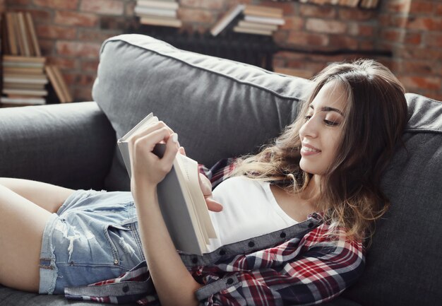 Jeune fille adolescente lisant un livre à la maison