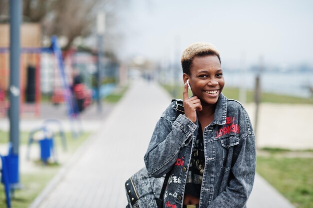 Jeune fille afro-américaine du millénaire en ville Heureuse femme noire avec des écouteurs sans fil Concept de génération Z