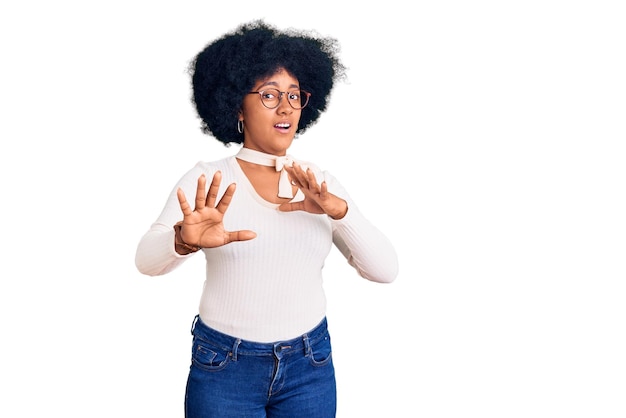 Photo gratuite jeune fille afro-américaine portant des vêtements décontractés et des lunettes effrayées et terrifiées par l'expression de la peur, arrêtez le geste avec les mains, criant sous le choc. notion de panique.