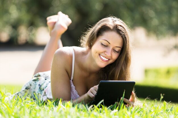 Jeune fille allongée sur l&#39;herbe avec ereader