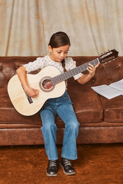 Photo gratuite jeune fille apprenant à jouer de la guitare à la maison