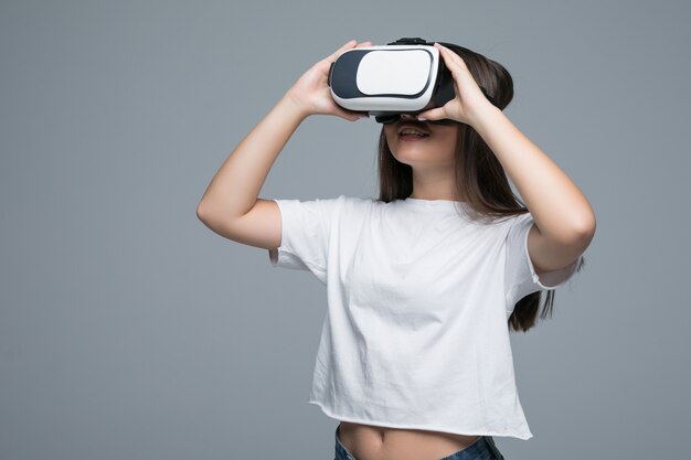 Jeune fille asiatique regardant VR et toucher à la main sur l'air sur fond gris