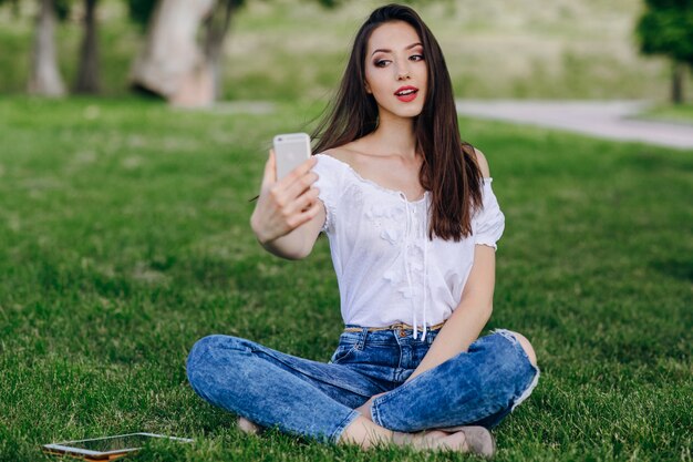 Jeune fille assise dans un parc faisant une photo automatique