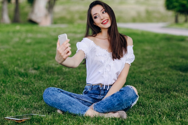 Jeune fille assise dans un parc faisant une photo automatique