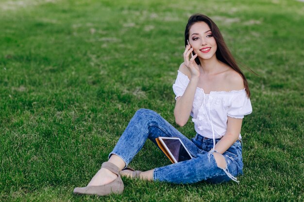 Jeune fille assise dans un parc de parler au téléphone