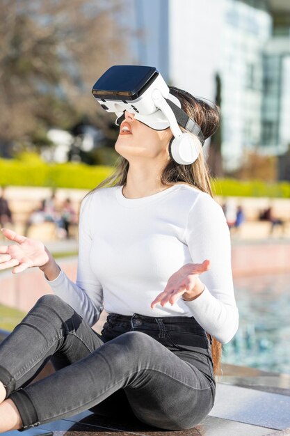 Une jeune fille assise dans la rue et portant des lunettes VR Photo de haute qualité