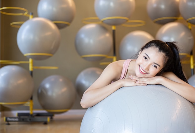 Photo gratuite la jeune fille assise se détendre avec le ballon dans la salle de gym.