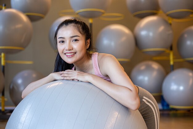 La jeune fille assise se détendre avec le ballon dans la salle de gym.