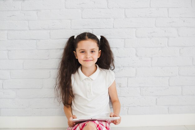 Jeune fille assise sur le sol souriante