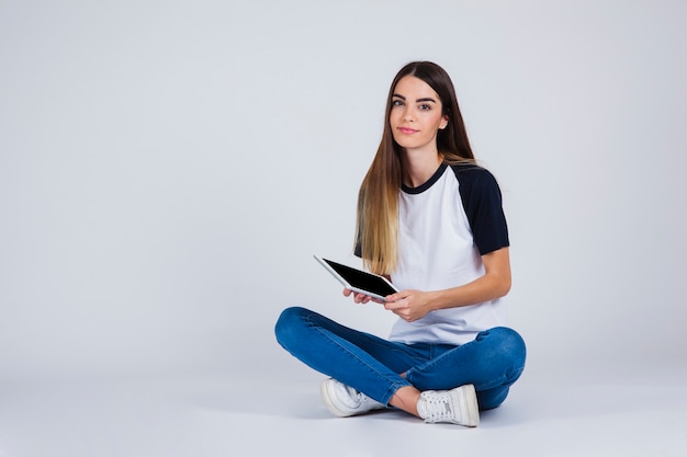 Photo gratuite jeune fille assise avec une tablette