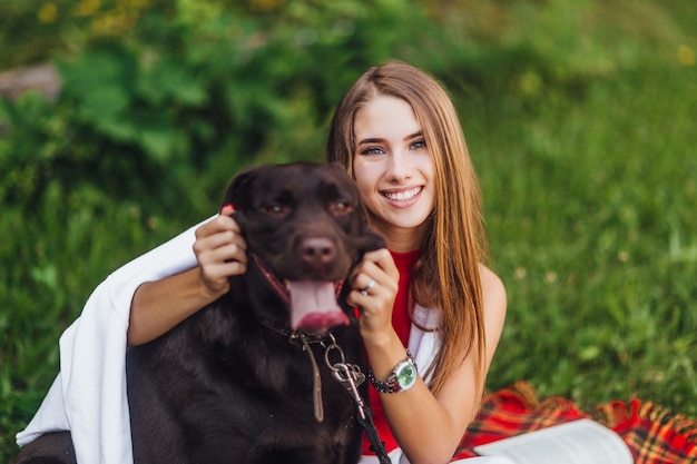 Jeune fille attirante souriant avec son chien labrador brun