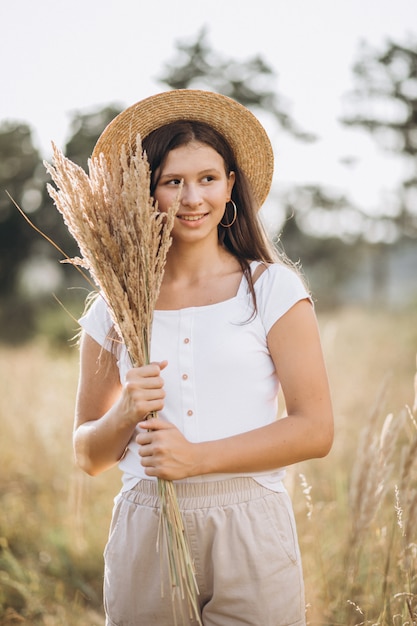 Jeune fille au chapeau dans un champ de blé