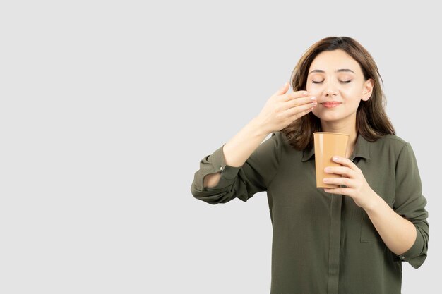 Jeune fille aux cheveux courts avec une tasse de café au lait debout et posant. photo de haute qualité