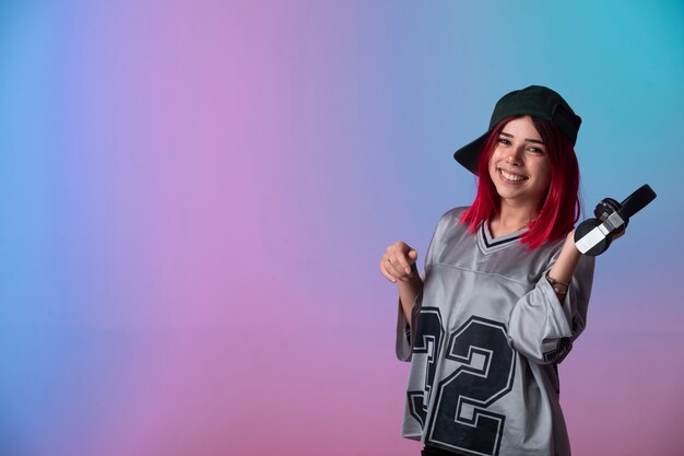 Jeune fille aux cheveux roses a l'air positif et tenant des écouteurs.