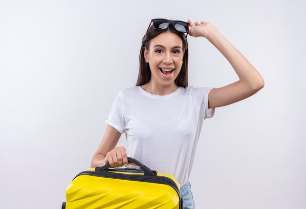 Jeune fille belle voyageur tenant valise positive et heureuse souriant gaiement