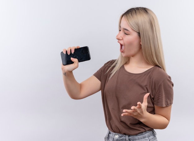 Jeune Fille Blonde Chantant à L'aide De Téléphone Comme Microphone Sur Un Mur Blanc Isolé Avec Copie Espace