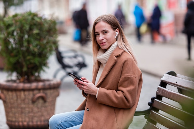 Jeune fille blonde, écouter de la musique sur les écouteurs à l'extérieur