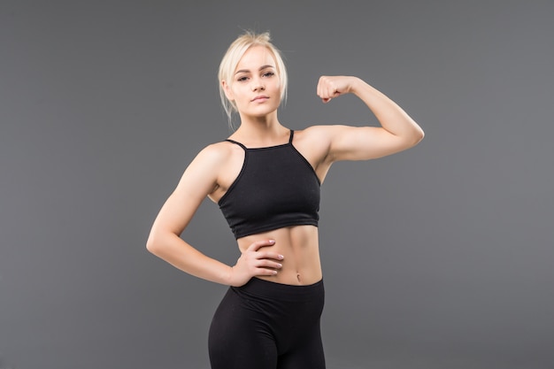 Jeune fille blonde fit sportive femme en vêtements de sport noir démostrate son fort étirement du corps musclé