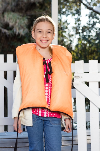 Jeune fille blonde en jeans et veste de sauvetage