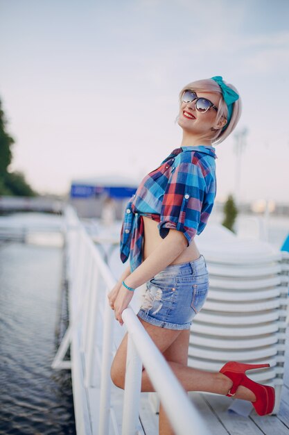 Jeune fille blonde posant souriante avec des lunettes de soleil