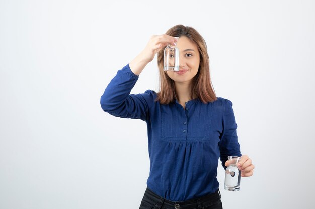 jeune fille en blouse bleue montrant un verre d'eau.