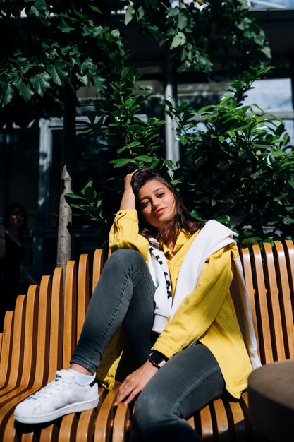 Jeune fille brune assise sur un banc dans la partie centrale de la vieille ville.