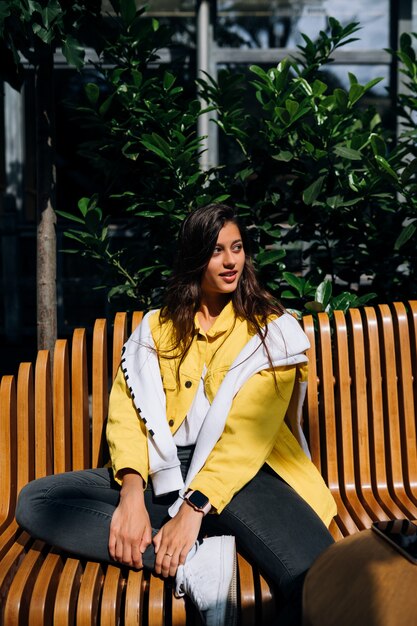 Jeune fille brune assise sur un banc dans la partie centrale de la vieille ville.