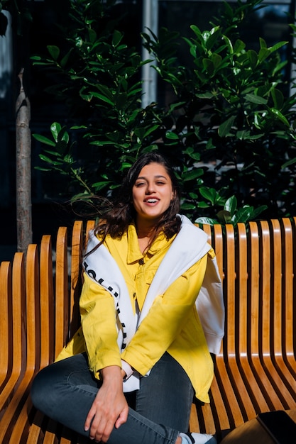 Jeune fille brune assise sur un banc dans la partie centrale de la vieille ville.